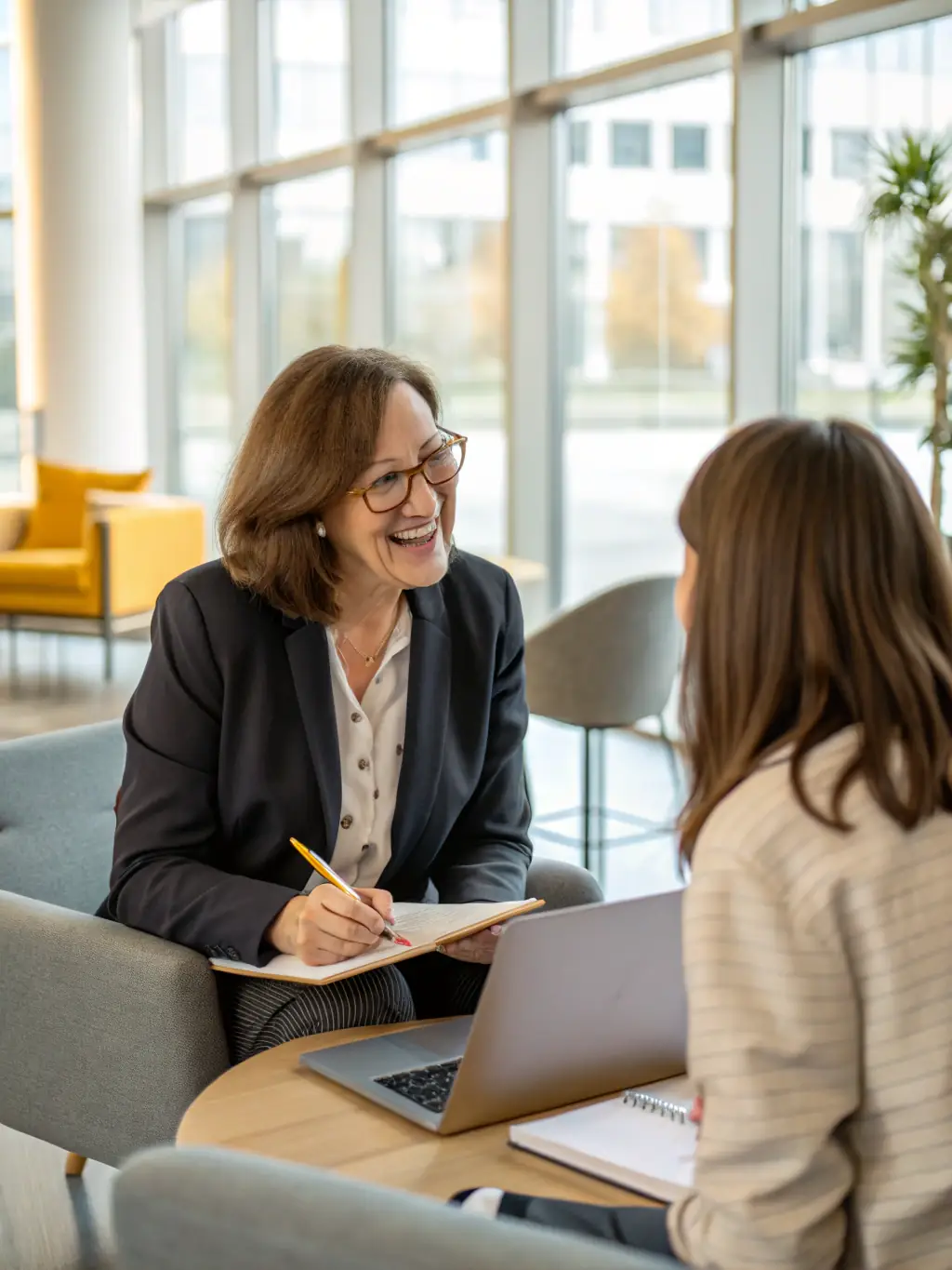 A professional executive in a modern office setting, engaged in a one-on-one coaching session with a leadership coach, discussing strategic goals and career development.